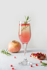 Sparkling wine, pomegranate, rosemary sprig on white table. Xmas drink.