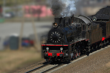 Fototapeta na wymiar Retro steam train in puffs of smoke rides by rail