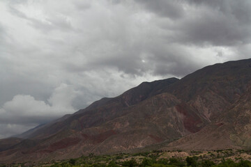 Cloudscape. Panorama view of the brown arid mountain under a dramatic cloudy sky. 