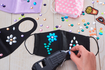 Woman attaching rhinestones onto black face masks