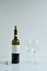 Bottle and two glasses of white wine standing on the white table