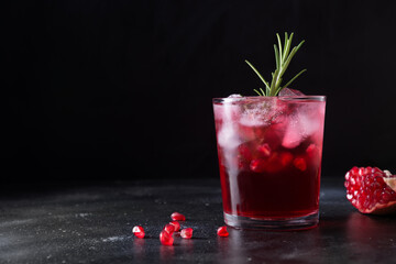 Pomegranate Christmas cocktail with rosemary, champagne, club soda on black table. Close up.
