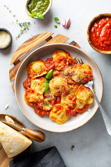 Ravioli in tomato sauce. Parmesan cheese, pesto sauce, Neapolitan sauce on a light gray table. Traditional Italian pasta. Top view.