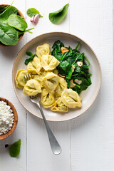 Ravioli with spinach and ricotta cheese on a white wooden table. Traditional Italian pasta. Top view.