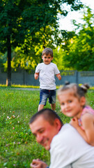 Family portrait of little boy, father and sister posing in the park.