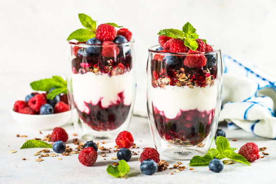 Parfait with granola, jam and fresh berries in the glass jar.