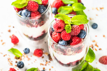 Parfait with granola, jam and fresh berries in the glass jar.