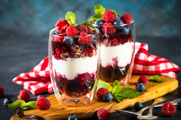 Parfait with granola, jam and fresh berries in the glass jar.