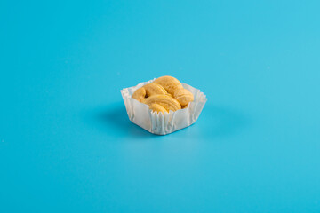 portion of cashews in a paper muffin cup on a blue background