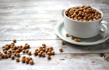 uncooked fresh dry chickpeas (garbanzo beans) in a cup on wooden background