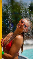 Beautiful young woman standing in shower in water park