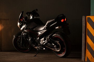 Sports black motorcycle on a background of an underground gray wall in the studio.