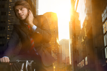 Handsome brunette business man commuting to work by bicycle wearing suit and tie