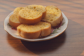 Garlic bread in a plate on the wood table and nature sunlight by window with copy space for text to use, Convenient and easy breakfast concept.
