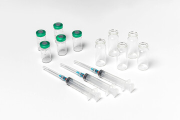 Medical vials with and without caps, hypodermic syringes isolated on white background. Treatment, cure background, top view