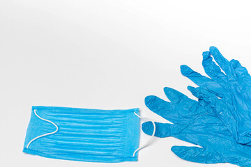 Blue medical face mask and a pair of gloves isolated on white background. Copy space