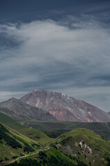Georgia.  Caucasus. Red rock mountain on background of green meadows, hills & blue sky with clouds in sunny summer day. Vertical wallpaper for telephone