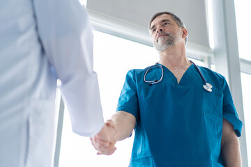 Two medical people handshaking at office, in hospital.