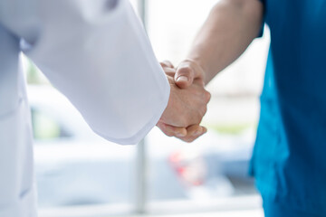 Two medical people handshaking at office, in hospital.
