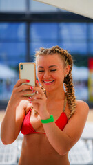 Young beautiful woman in a swimsuit talking laughing on phone in water park