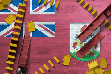 Bermuda flag with national background with dominoes on wooden table. Top view. Concept of game.