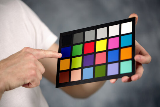 The model holds a color card in its hands for correct color transfer during further color correction. Closeup of a Colorchecker card in the hands