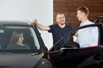 Fototapeta na wymiar A sales representative explains the pros and cons of a brand new car at a dealership. Concept professionalism agreement contract leasing renting retail car sales