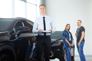 Fototapeta na wymiar Selective focus Manager of a car dealership showing a luxury car to spouses in a car dealership. The concept of professionalism, the lease agreement, car rental, retail sales