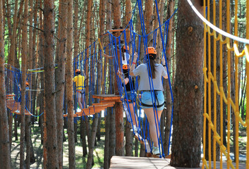 Children on a high rope obstacle course in the forest. Rope town. Rope park. 