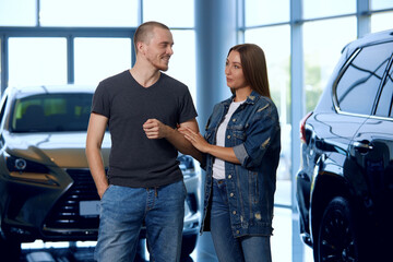 A married couple chooses a new car at a dealership. Concept of buying a new car