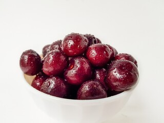 Bright juicy red cherry on a white background in drops of water.