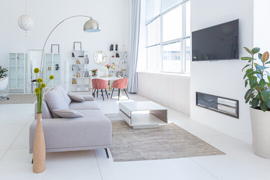 Cozy luxury modern interior design of a studio apartment in extra white colors with fashionable expensive furniture in a minimalist style. white tiled floor, kitchen, relaxation area and workplace