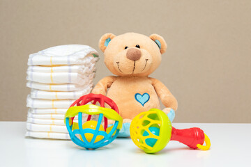Stack of diapers, cute teddy bear with toys on table. set for boy girl for baby shower with copy space