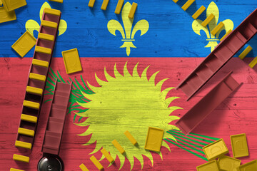 Guadeloupe flag with national background with dominoes on wooden table. Top view. Concept of game.