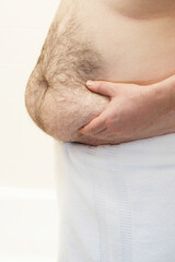 Barechested man with hands on belly