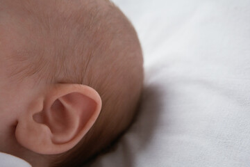 Baby lying on bed close up of ear