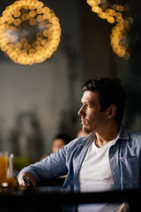 Stylish confident entrepreneur sitting in restaurant in thoughtful pose and looking away into window