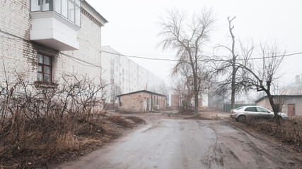 Foggy morning in a provincial Russian city. Barns, houses, car.