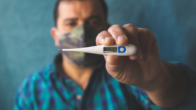 Man With Mask In Times Of COVID-19 Taking Body Temperature