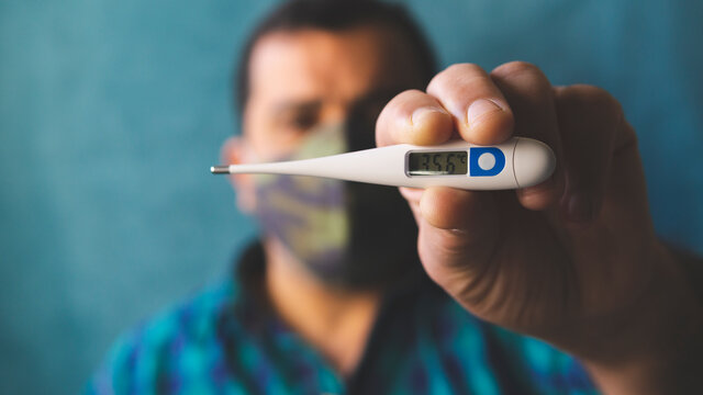 Man With Mask In Times Of COVID-19 Taking Body Temperature