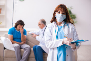 Two doctors visiting sick young man at home