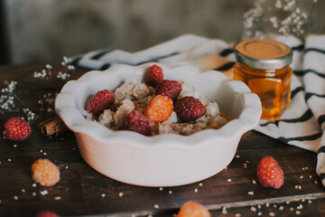 A delicious and healthy breakfast with raspberries and honey. Oatmeal for breakfast. Morning aesthetics and beautiful layout on a wooden table.