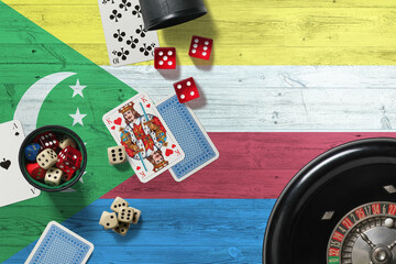 Comoros casino theme. Aces in poker game, cards and chips on red table with national wooden flag background. Gambling and betting.