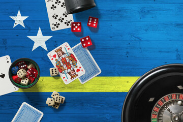 Curacao casino theme. Aces in poker game, cards and chips on red table with national wooden flag background. Gambling and betting.