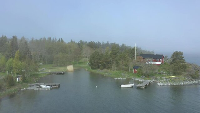 Aerial view of cabin along shoreline in the archipelago, misty weather