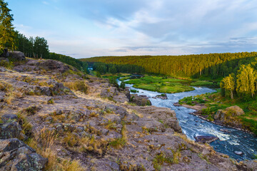 soft sun rays in evening over beautiful valley with mountain river and many rapids. Ural, Russia,