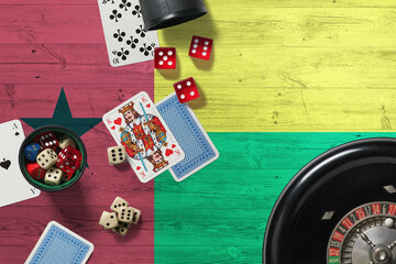 Guinea casino theme. Aces in poker game, cards and chips on red table with national wooden flag background. Gambling and betting.
