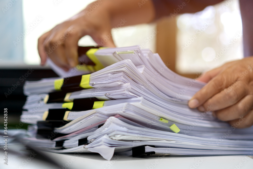 Wall mural Stacks documents of paper files, Businessman hands working in messy bureaucracy and searching information on office, Accounting budget report file, arranging unfinished of paperwork on busy overwork