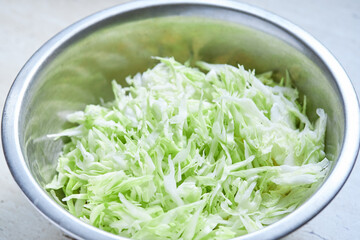 fresh sliced cabbage in a bowl on a kitchen table. domestic cooking. healthy lifestyles concept.