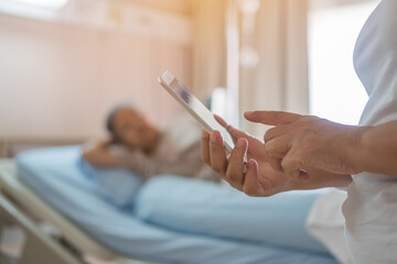 Fototapeta na wymiar Hospital Patients woman senior using smart phone for reading news in mobile with another patient on hospital bed for Telemedicine Care advice, Health care technology concept